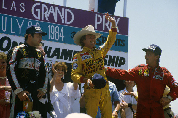 Keke Rosberg, 1st position, wears a stetson on the podium. René Arnoux, 2nd position, and Elio de Angelis, 3rd position, are also on the podium. Actress Linda Gray, who played Sue Ellen Ewing in Dallas, looks on. Keke Rosberg, 1st position, wears a stetson on the podium. René Arnoux, 2nd position, and Elio de Angelis, 3rd position, are also on the podium. Actress Linda Gray, who played Sue Ellen Ewing in Dallas, looks on.