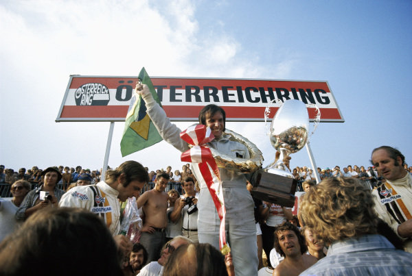 Emerson Fittipaldi celebrates victory on the podium with second place Denny Hulme (R) and third place Peter Revson (L).